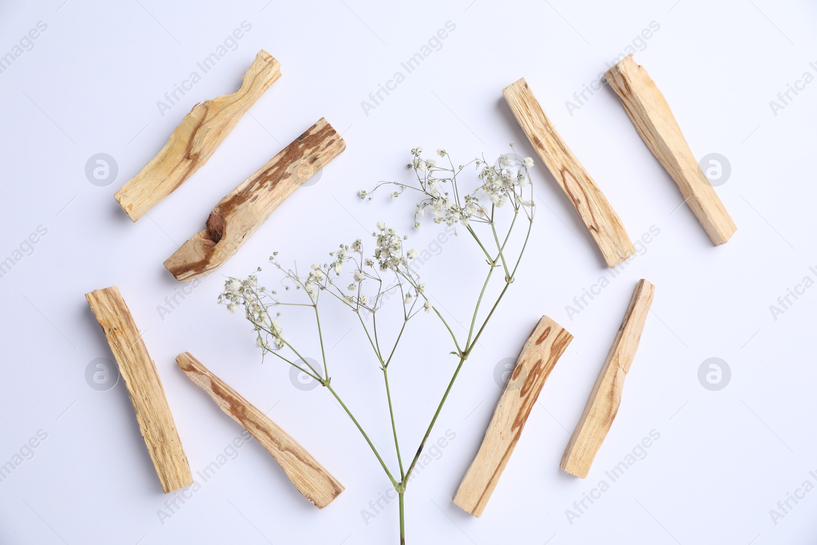 Photo of Palo santo sticks and gypsophila flowers on white background, flat lay