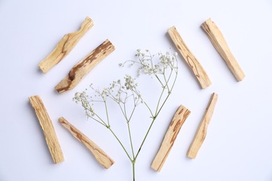 Photo of Palo santo sticks and gypsophila flowers on white background, flat lay