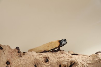 Photo of Smoldering palo santo stick and snag on beige background, closeup. Space for text