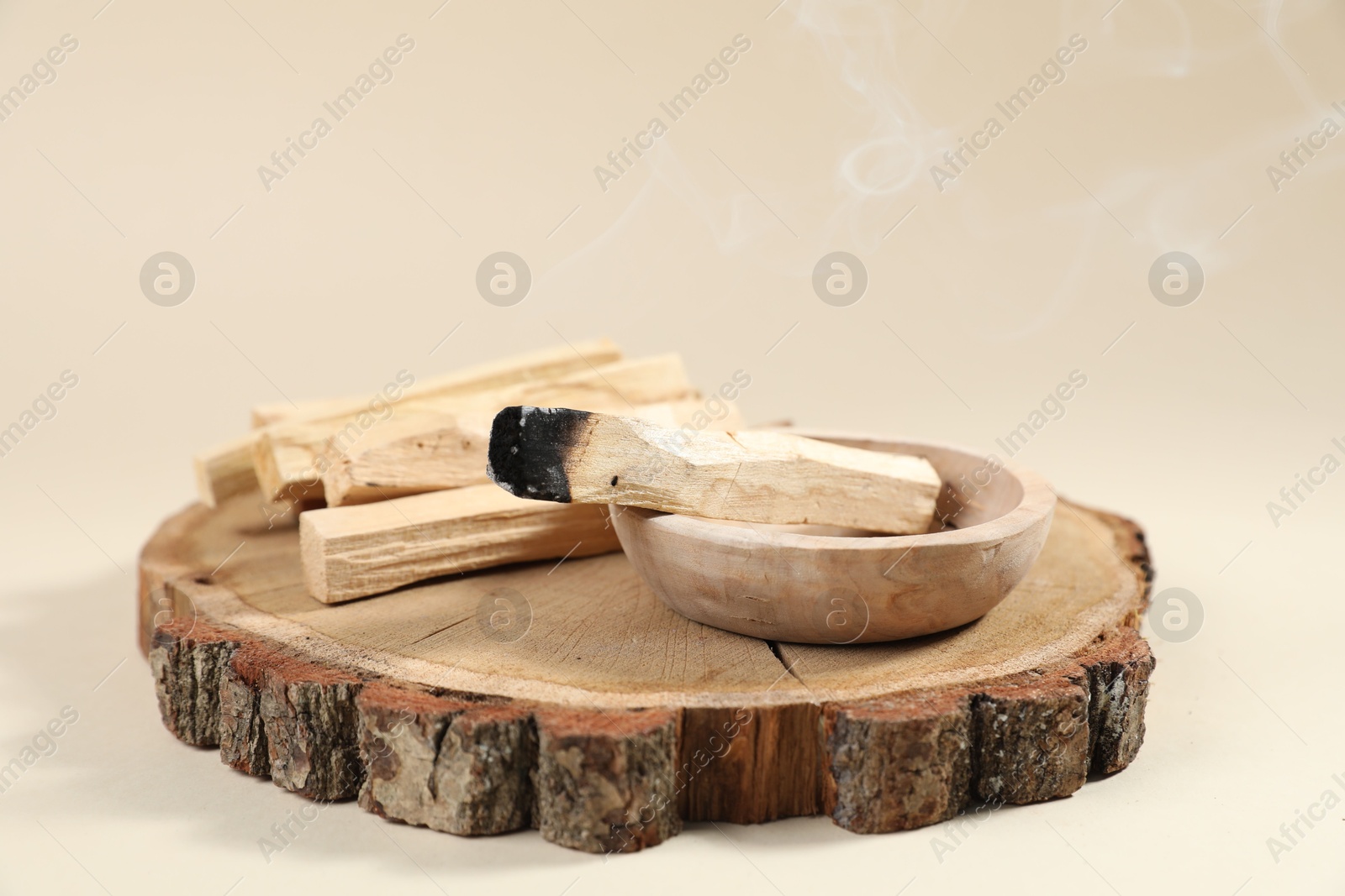 Photo of Palo santo sticks and smoldering one on beige background, closeup