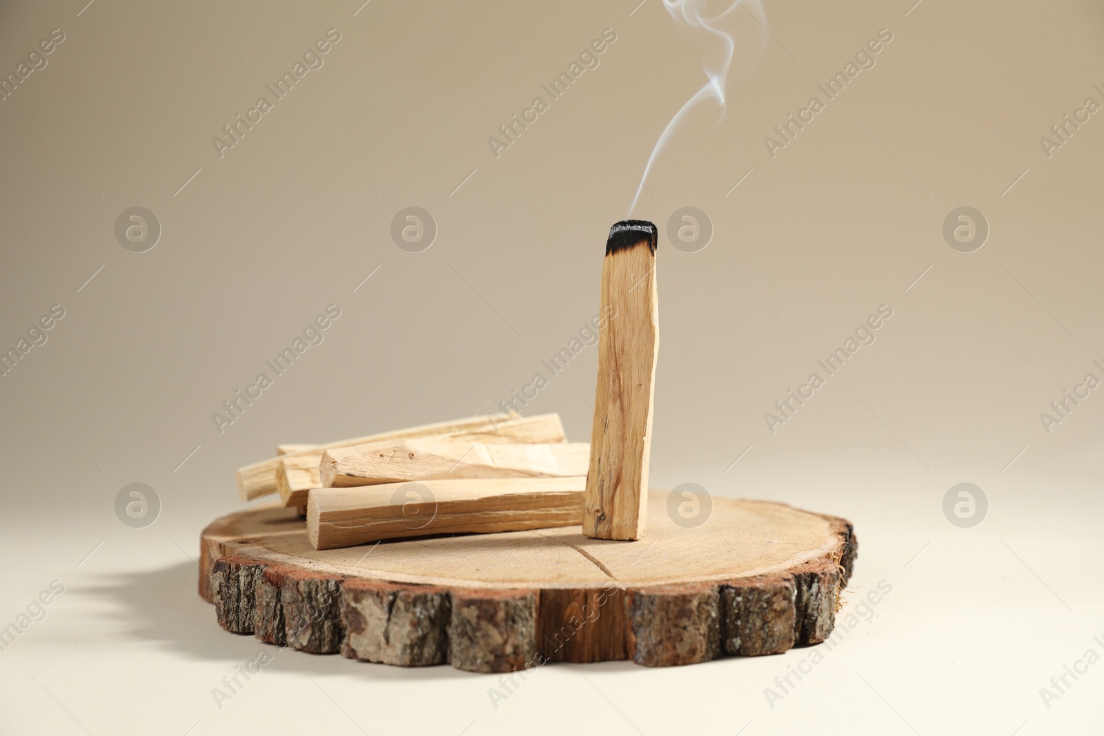 Photo of Palo santo sticks and smoldering one on beige background, closeup