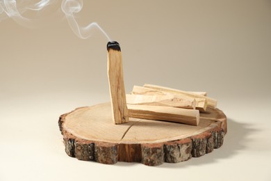 Photo of Palo santo sticks and smoldering one on beige background, closeup