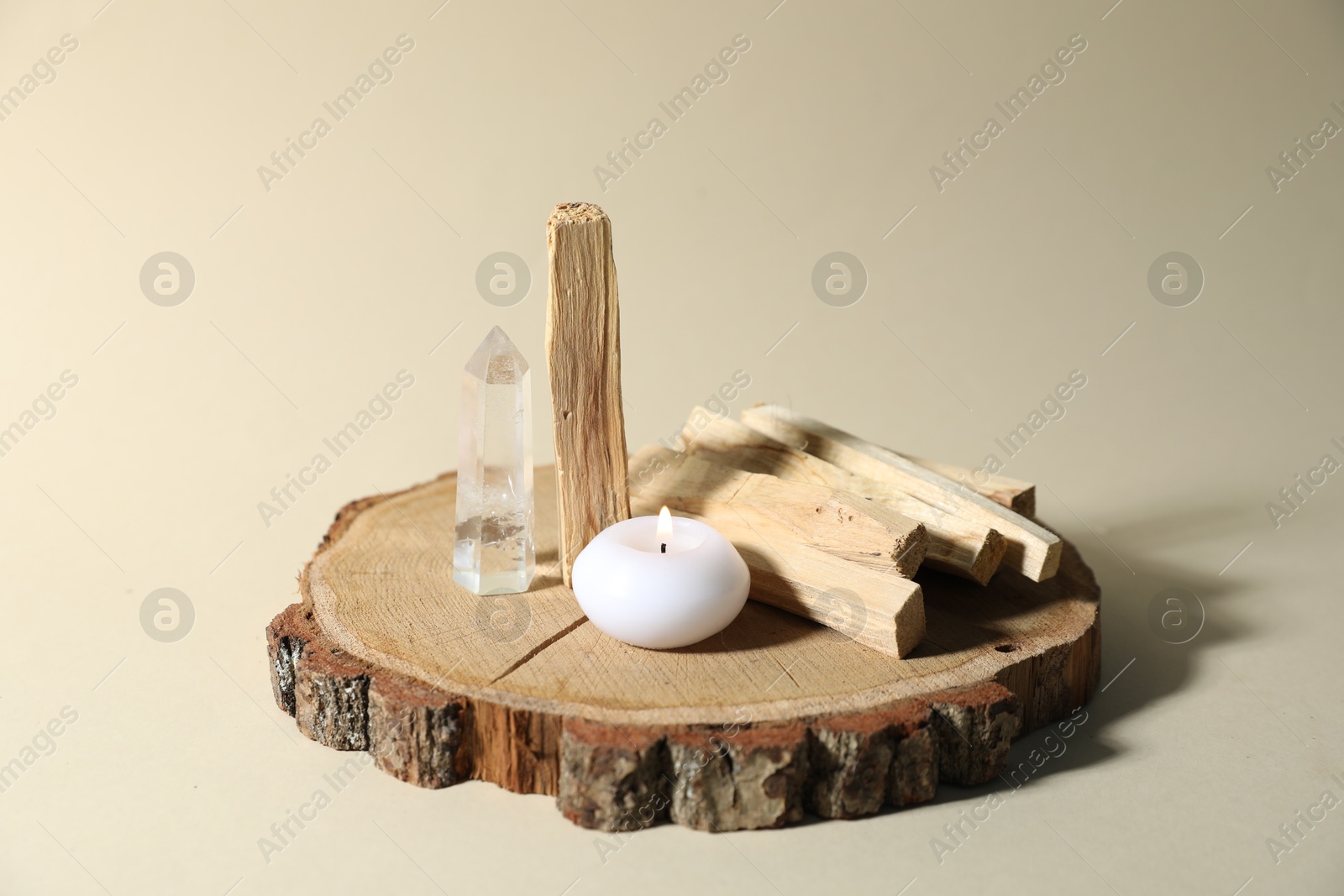 Photo of Palo santo sticks, gemstone and burning candle on beige background, closeup