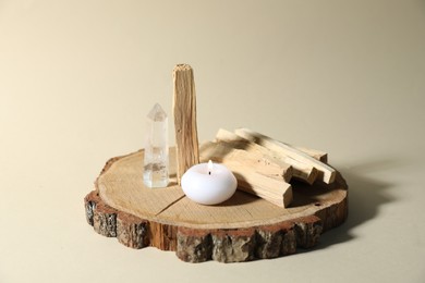 Photo of Palo santo sticks, gemstone and burning candle on beige background, closeup