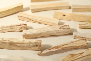 Photo of Palo santo sticks on beige background, closeup