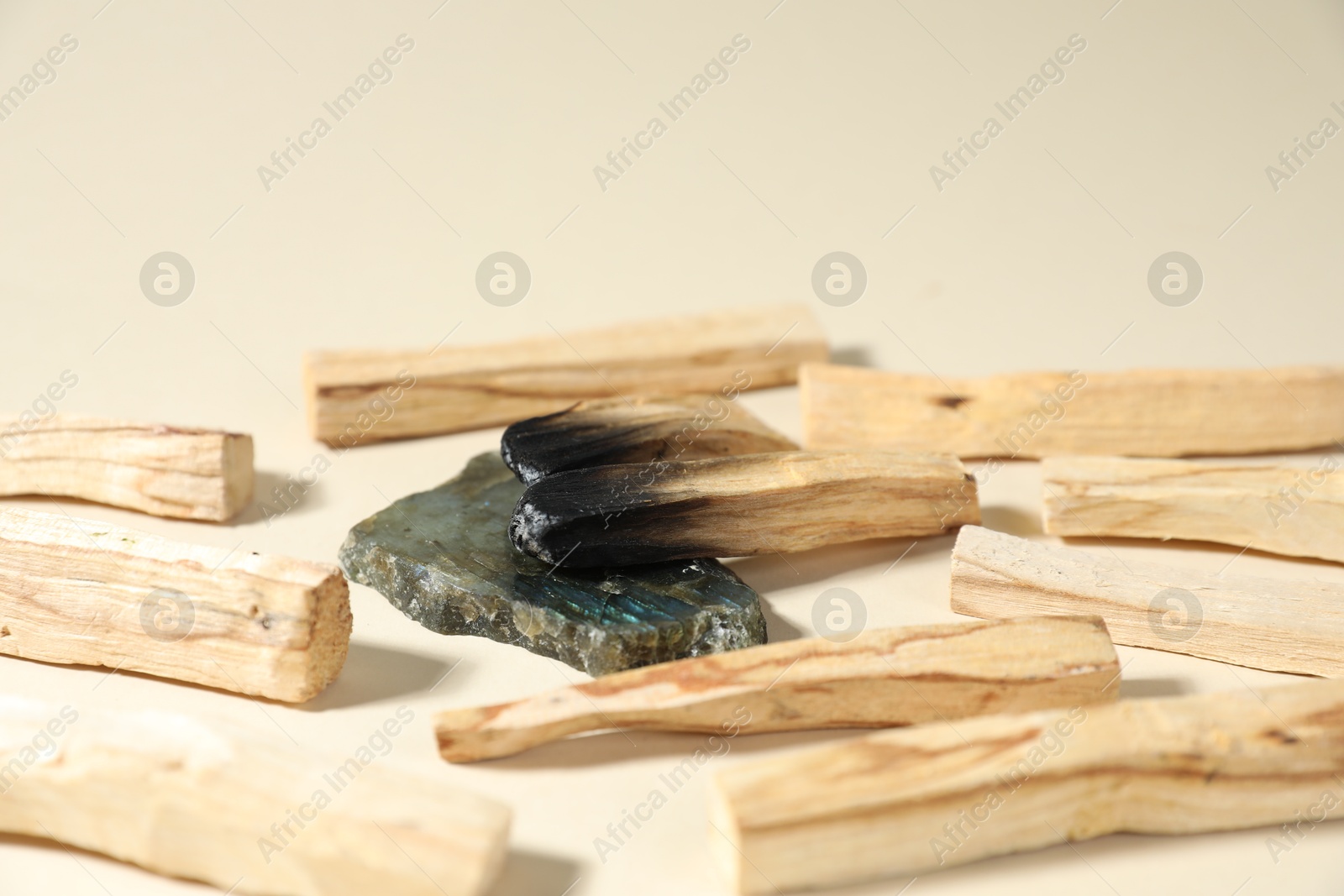 Photo of Palo santo sticks and gemstone on beige background, closeup