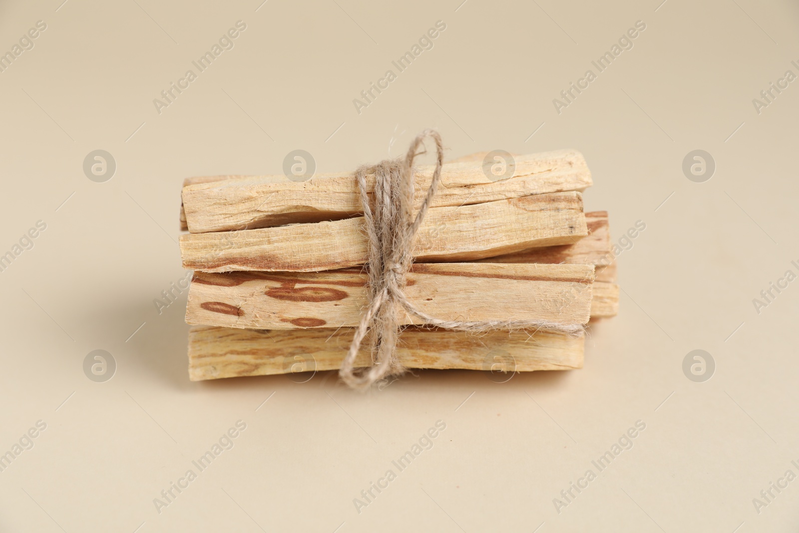 Photo of Bunch of palo santo sticks on beige background, closeup