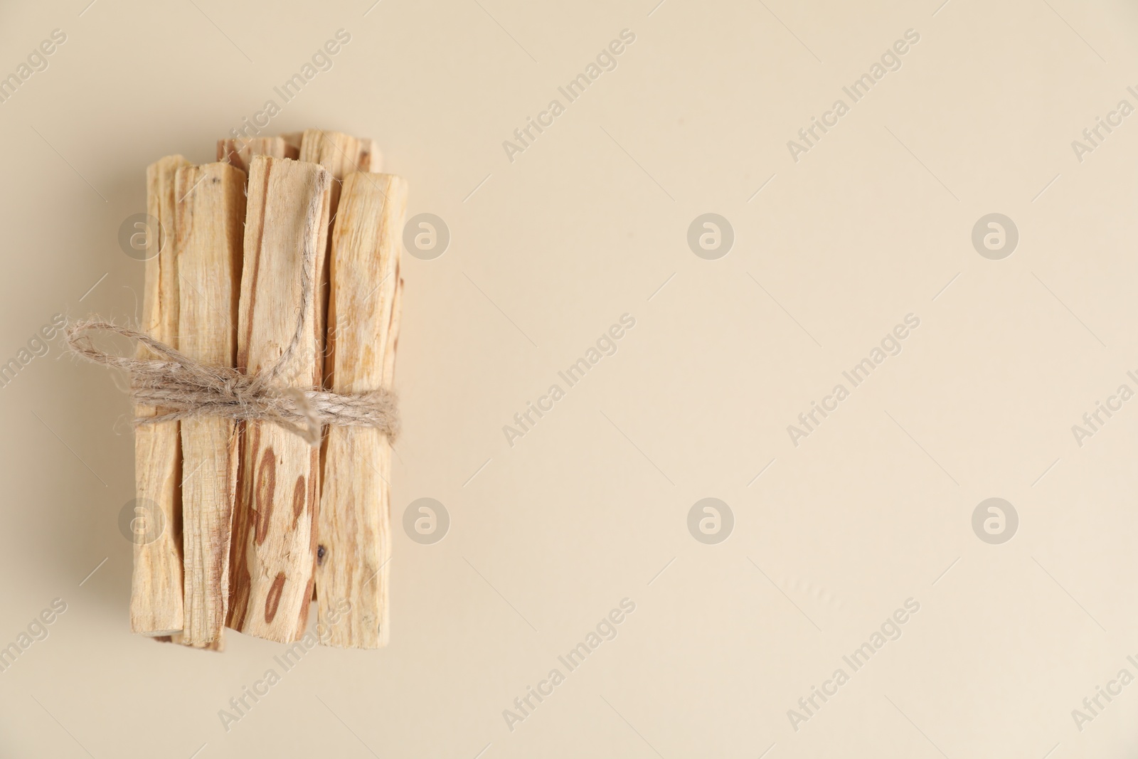 Photo of Bunch of palo santo sticks on beige background, top view. Space for text