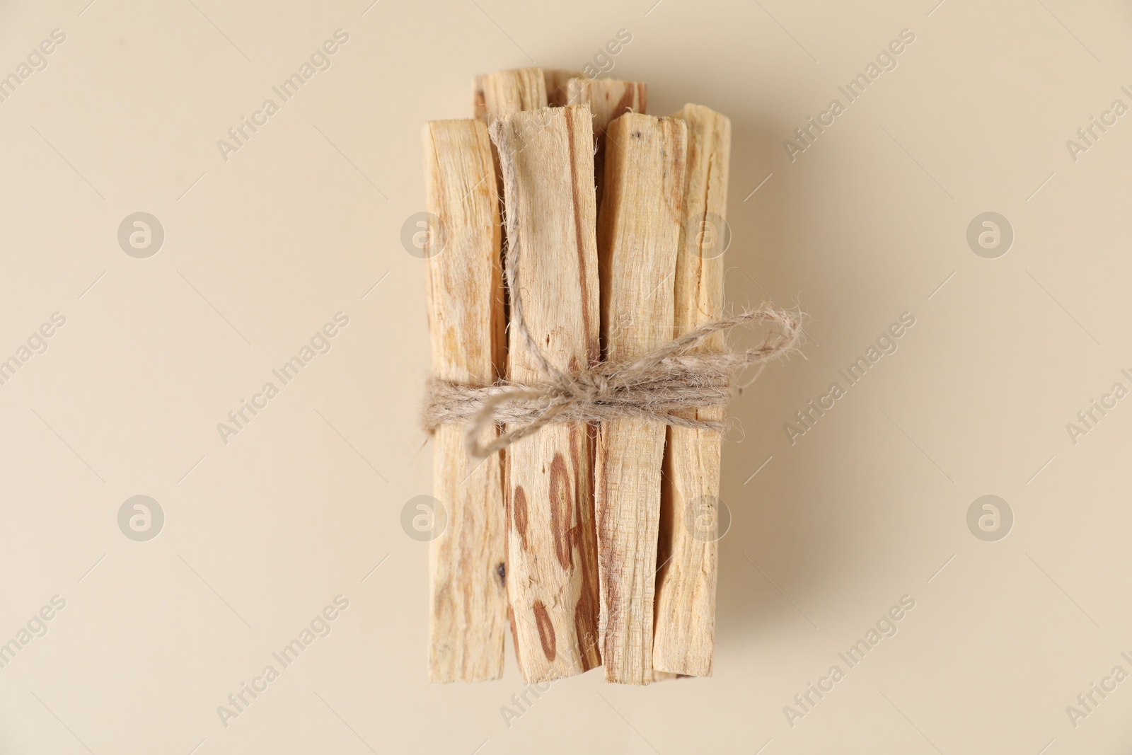 Photo of Bunch of palo santo sticks on beige background, top view