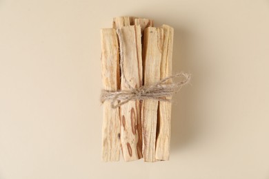 Photo of Bunch of palo santo sticks on beige background, top view