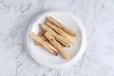 Photo of Palo santo sticks on white marble table, top view