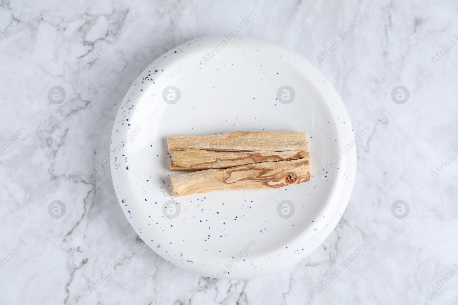 Photo of Palo santo sticks on white marble table, top view