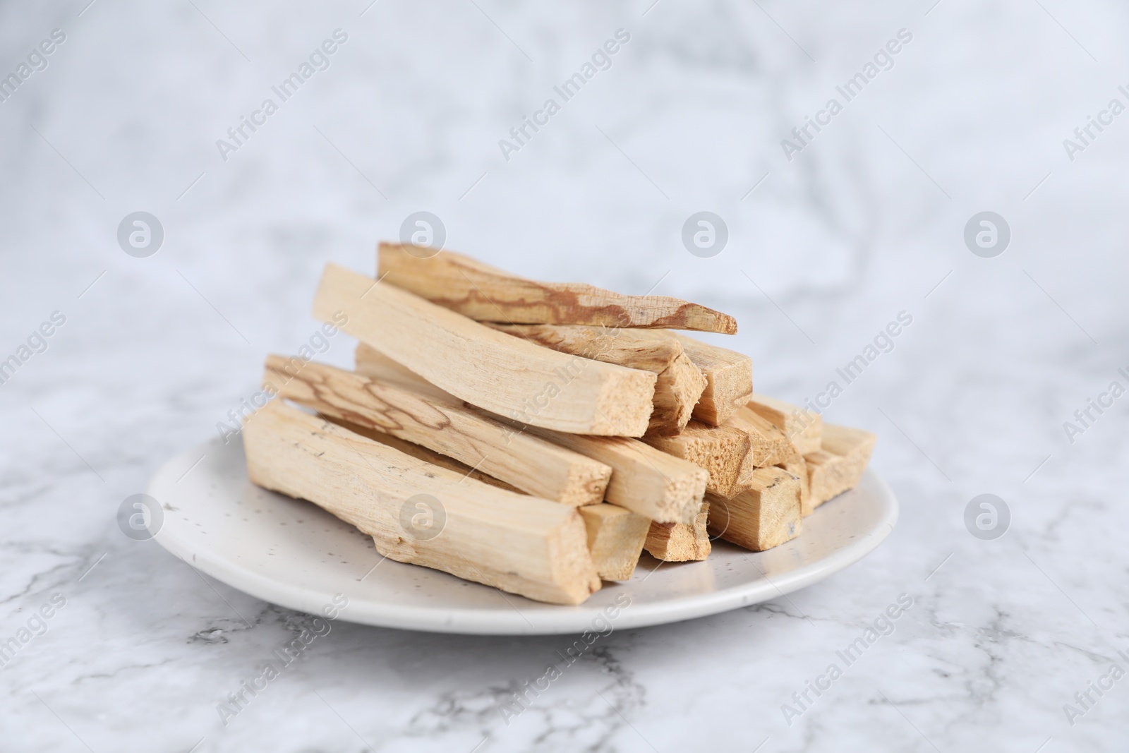 Photo of Palo santo sticks on white marble table, closeup