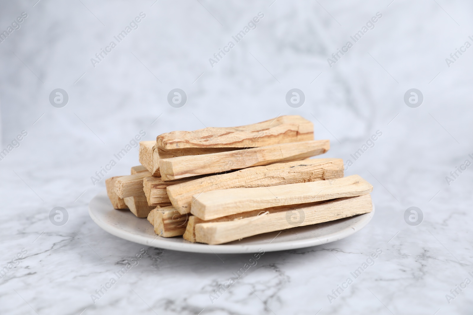 Photo of Palo santo sticks on white marble table, closeup