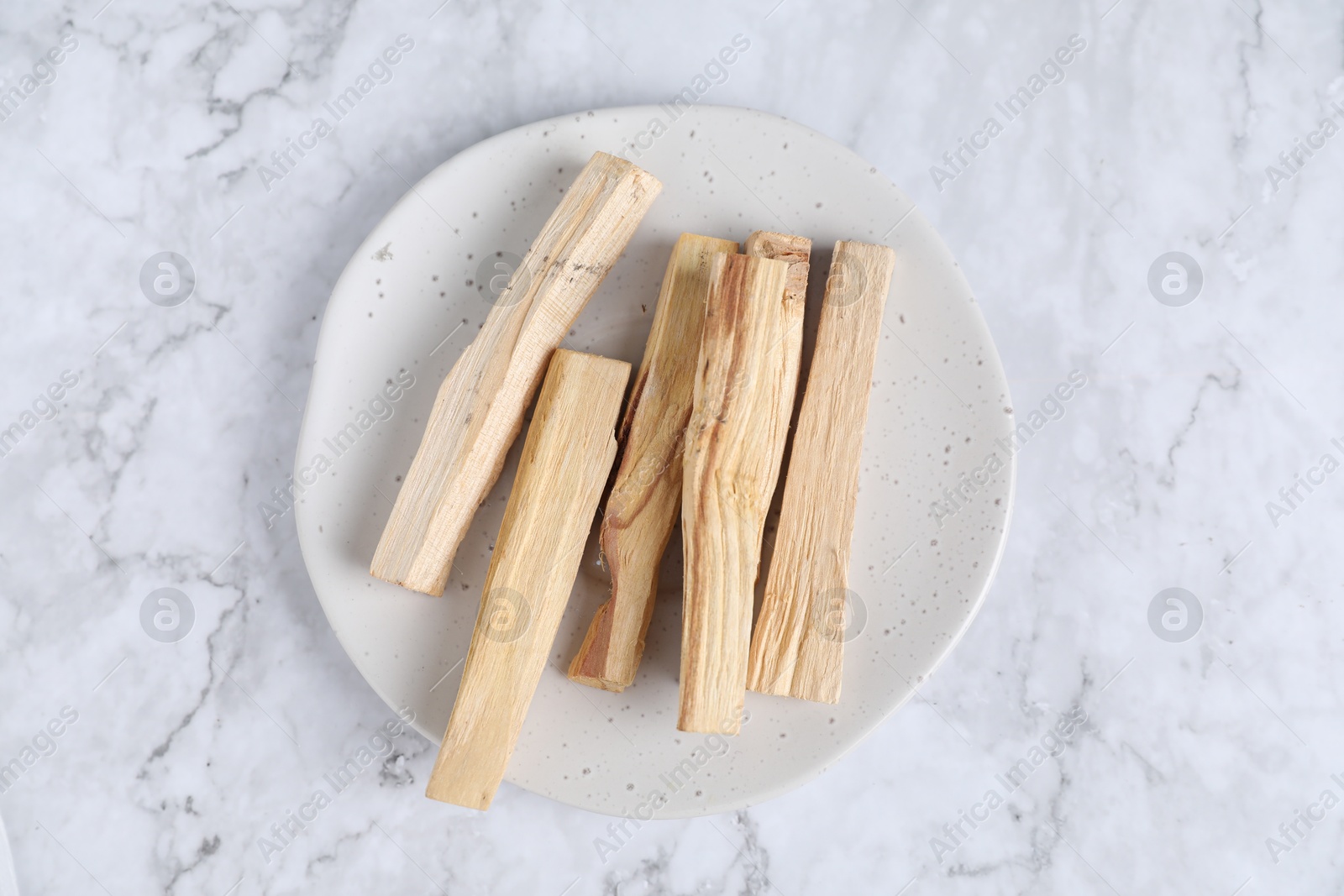 Photo of Palo santo sticks on white marble table, top view