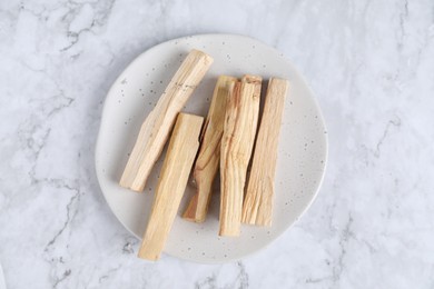 Photo of Palo santo sticks on white marble table, top view