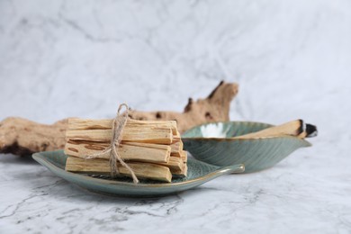 Photo of Bunch of palo santo sticks and snag on white marble table, closeup