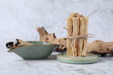 Photo of Bunch of palo santo sticks and snag on white marble table