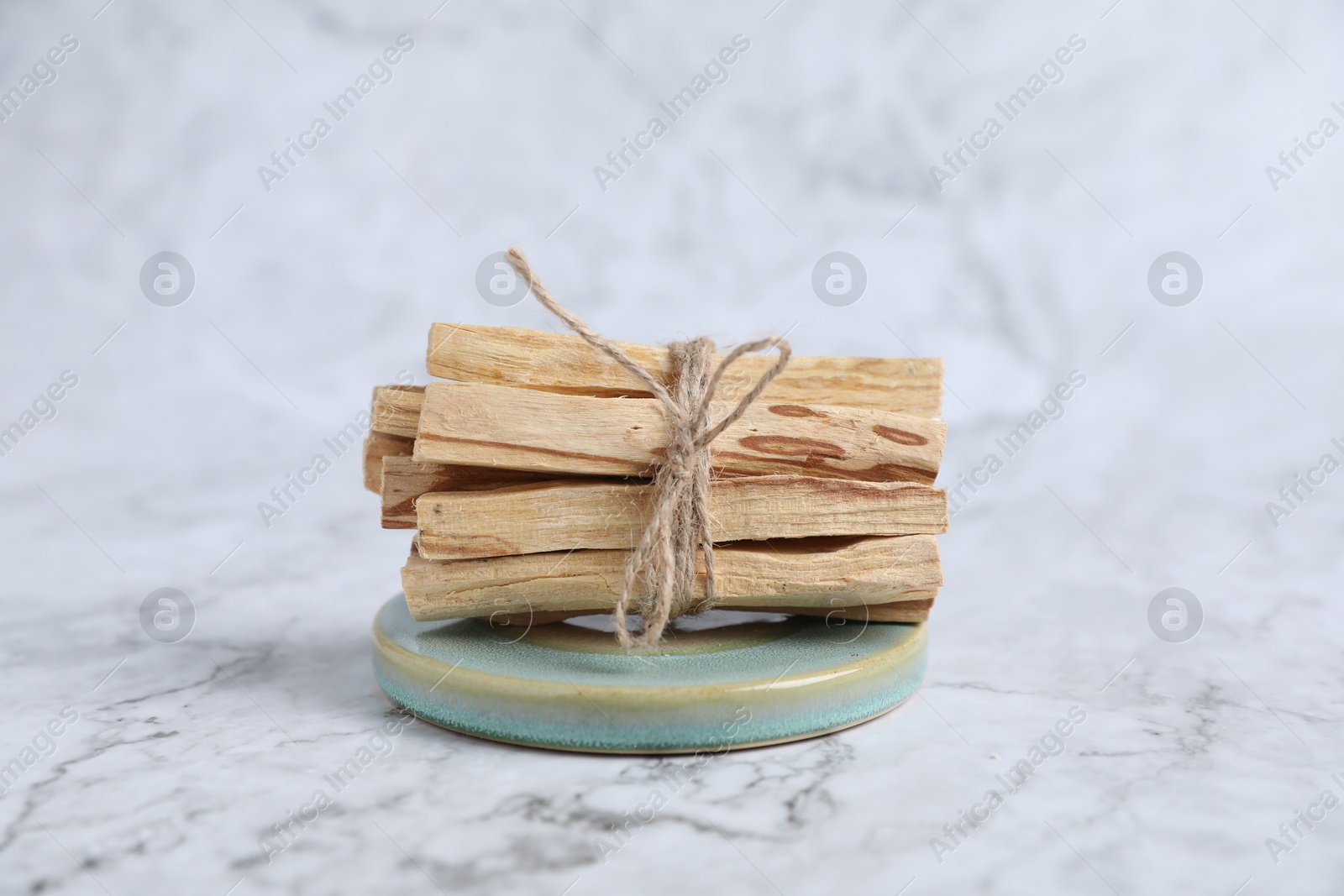 Photo of Bunch of palo santo sticks on white marble table, closeup