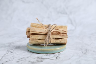 Photo of Bunch of palo santo sticks on white marble table, closeup