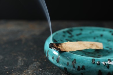 Photo of Smoldering palo santo stick on dark table, closeup. Space for text