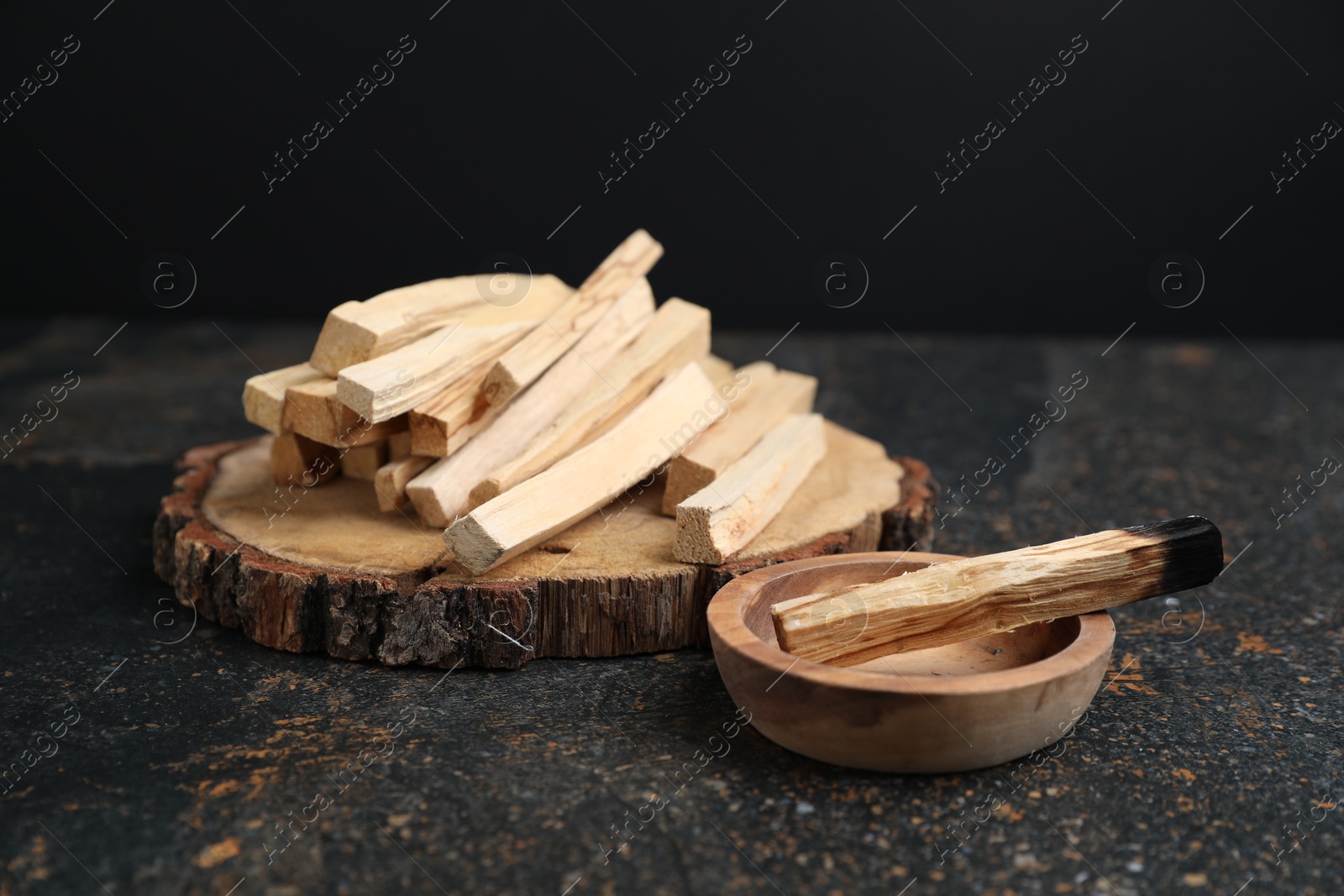 Photo of Palo santo sticks and burnt one on dark table, closeup