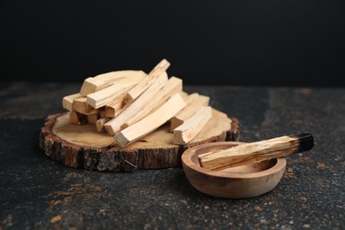 Photo of Palo santo sticks and burnt one on dark table, closeup