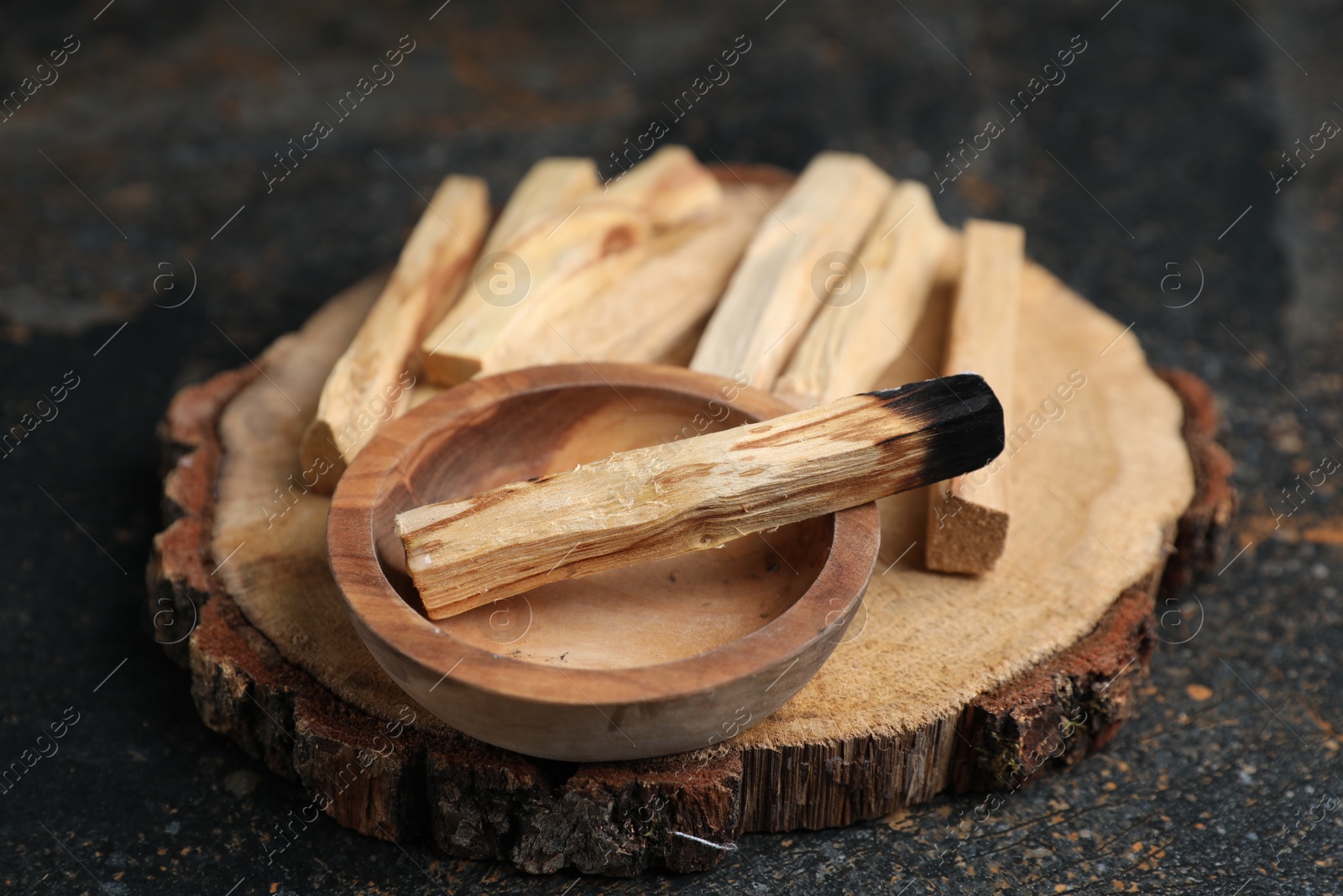 Photo of Palo santo sticks and burnt one on dark table, closeup