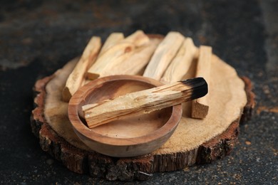 Photo of Palo santo sticks and burnt one on dark table, closeup