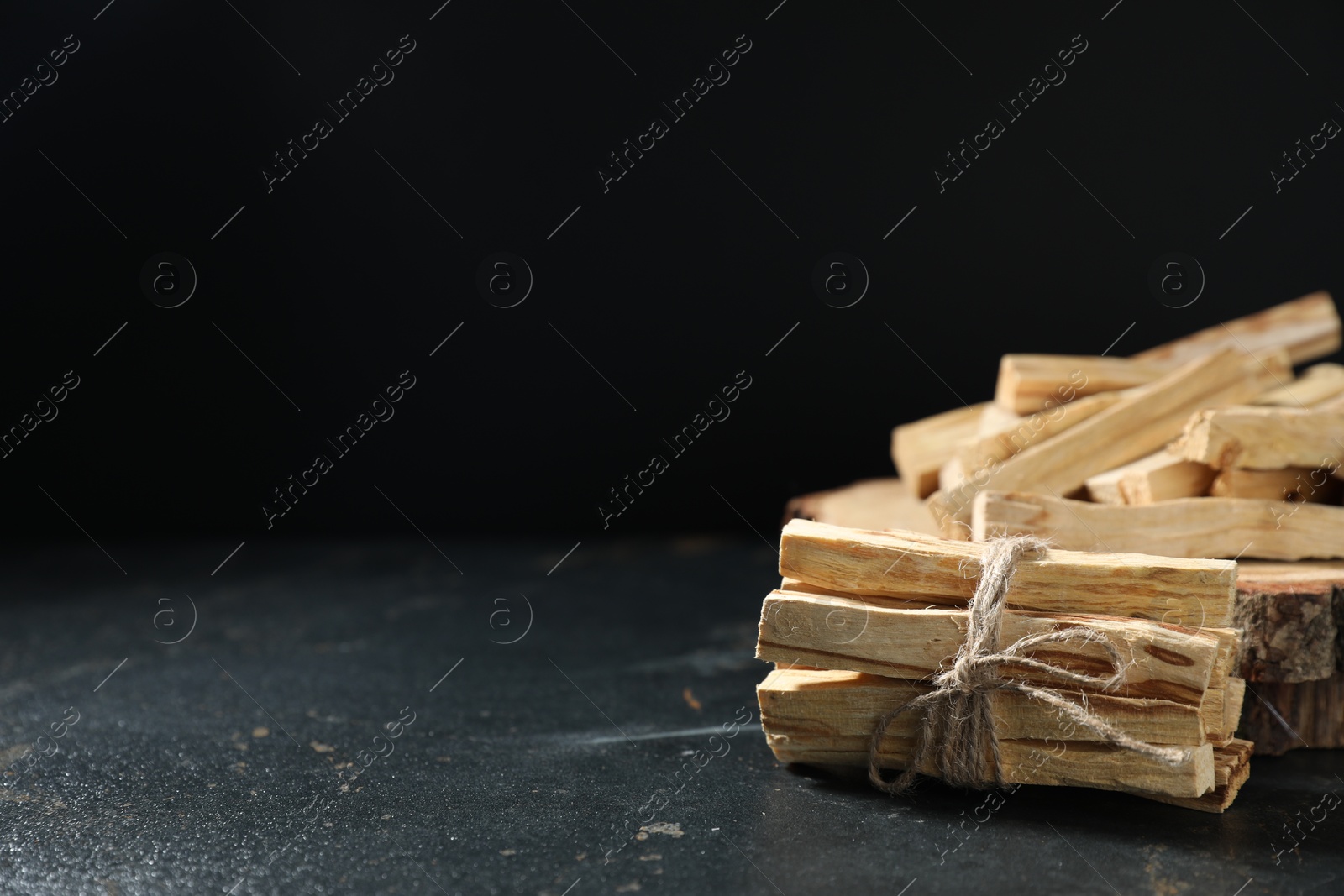 Photo of Palo santo sticks on dark table, closeup. Space for text