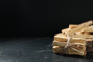 Photo of Palo santo sticks on dark table, closeup. Space for text