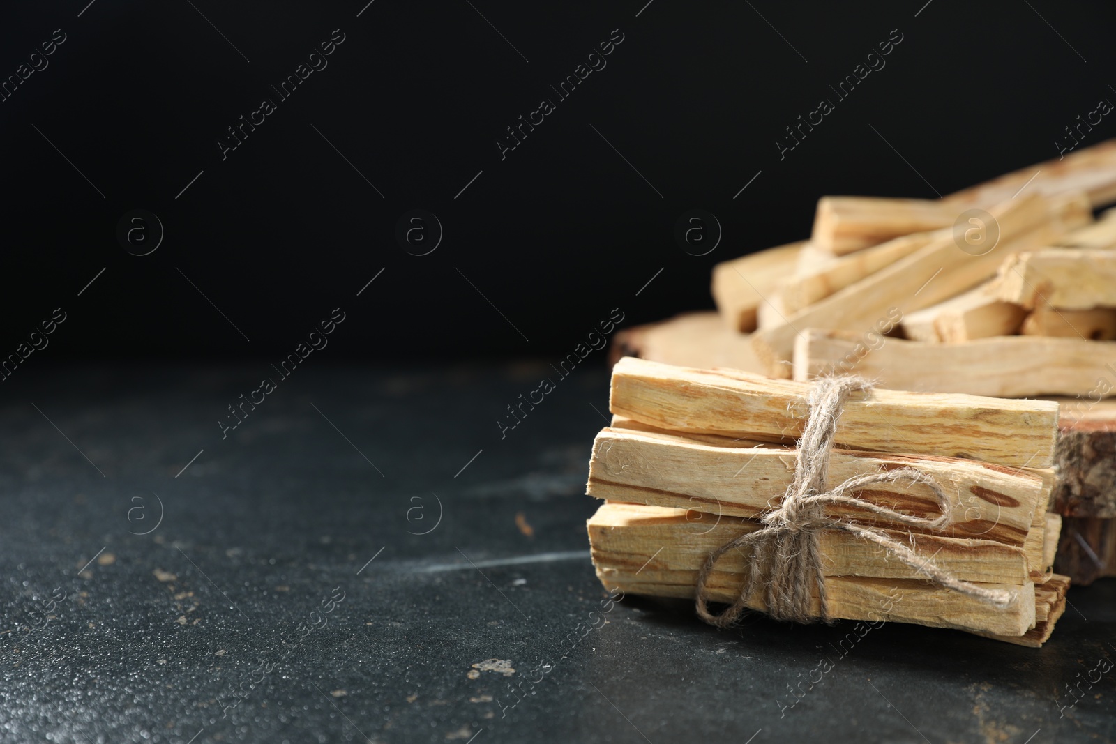 Photo of Palo santo sticks on dark table, closeup. Space for text