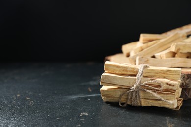 Photo of Palo santo sticks on dark table, closeup. Space for text