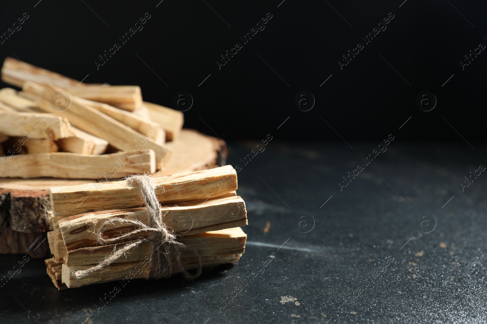 Photo of Palo santo sticks on dark table, closeup. Space for text