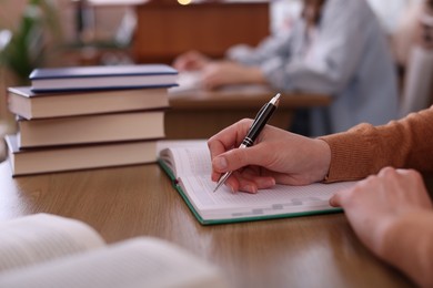 Photo of Woman taking notes at desk in library, closeup