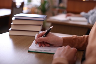 Photo of Woman taking notes at desk in library, closeup