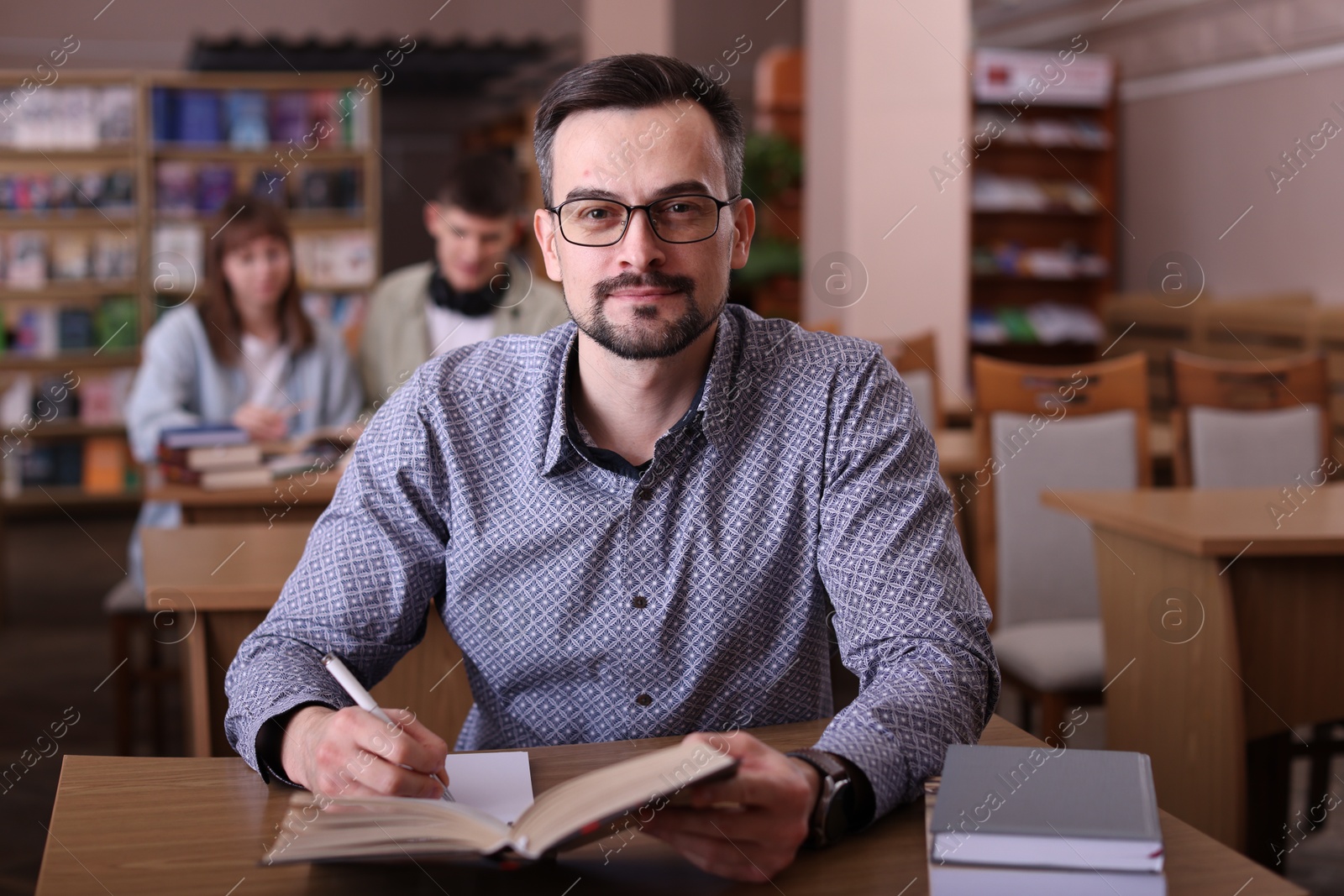 Photo of Portrait of handsome man with book at desk in public library