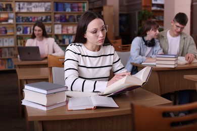 Beautiful woman reading book at desk in public library