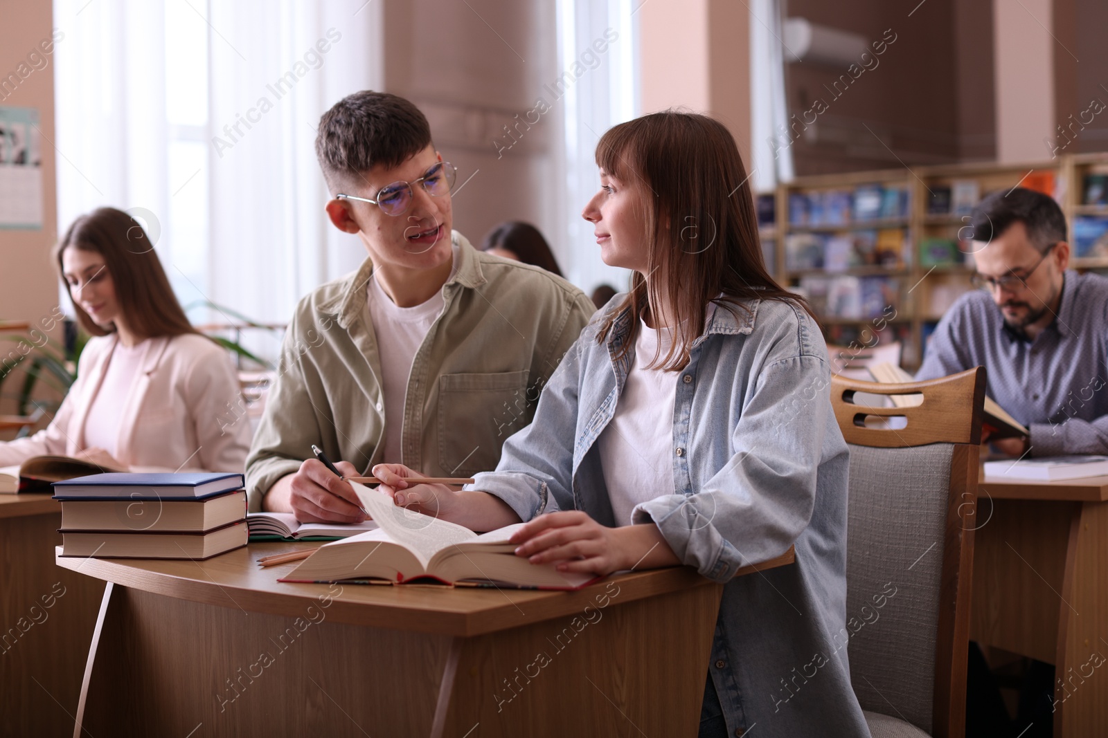 Photo of People reading different books at desks in public library