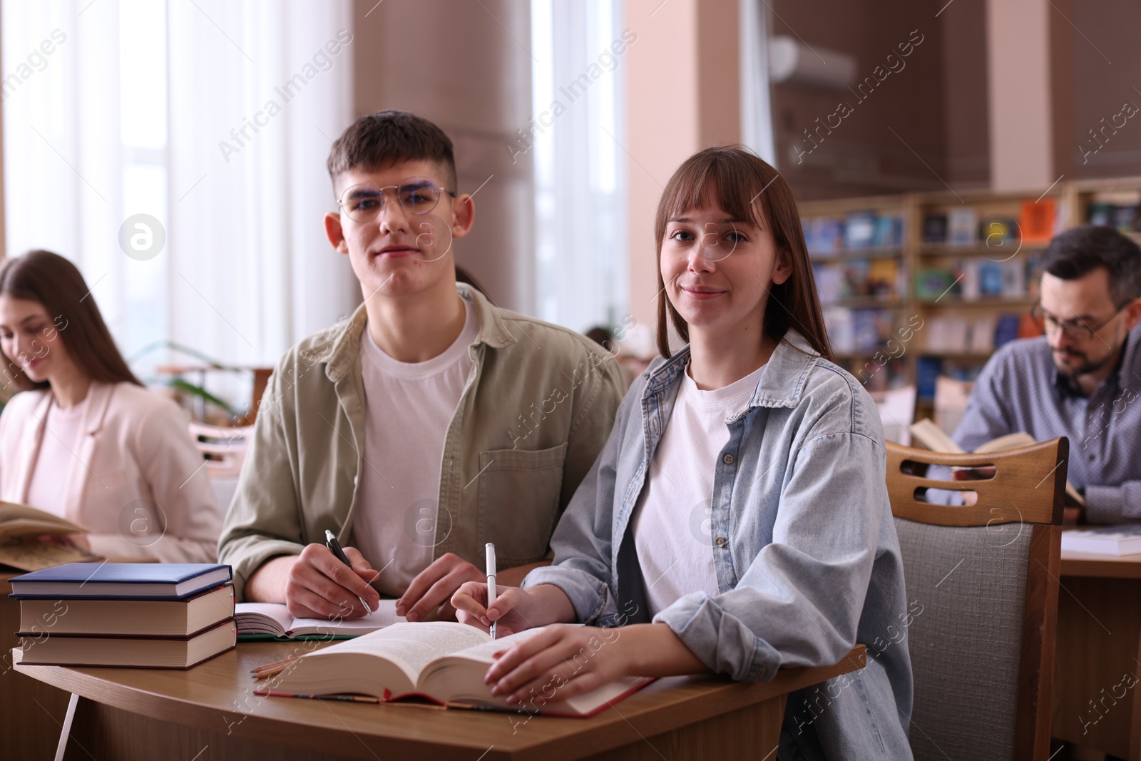 Photo of Portrait of young couple with books at desk in public library