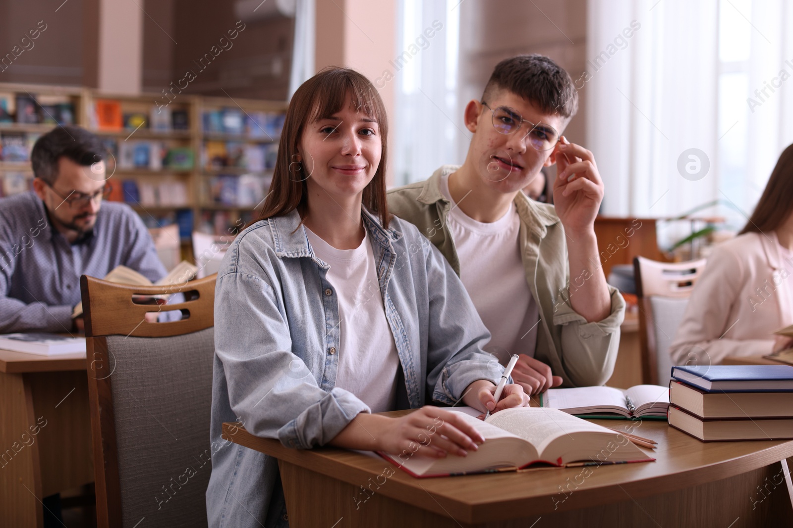 Photo of Portrait of young couple with books at desk in public library