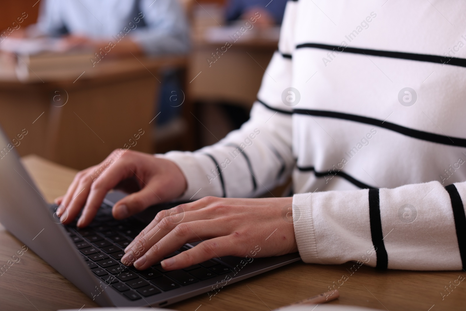 Photo of Woman typing on laptop at desk in library, closeup