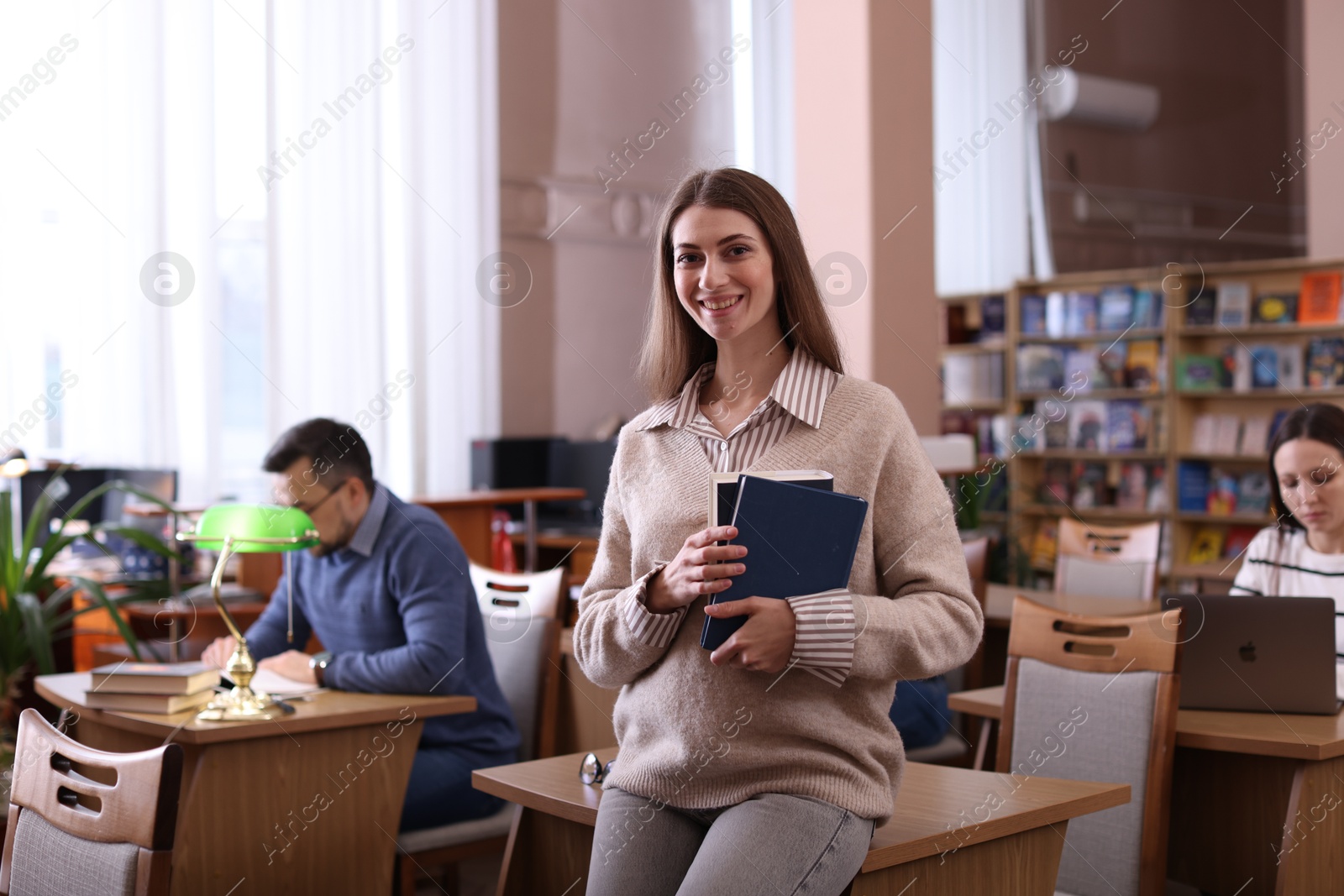 Photo of Portrait of smiling woman with books in library