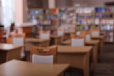 Photo of Desks and chairs in public library room, blurred view