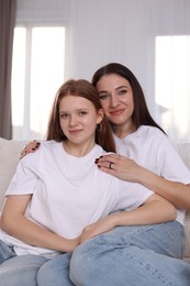 Portrait of beautiful mother with teenage daughter on sofa at home