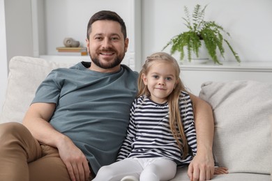 Happy father and his cute little daughter on sofa at home