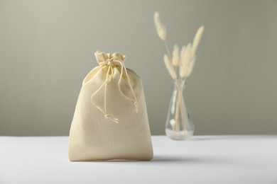 Photo of Beige burlap sack on white surface against gray background