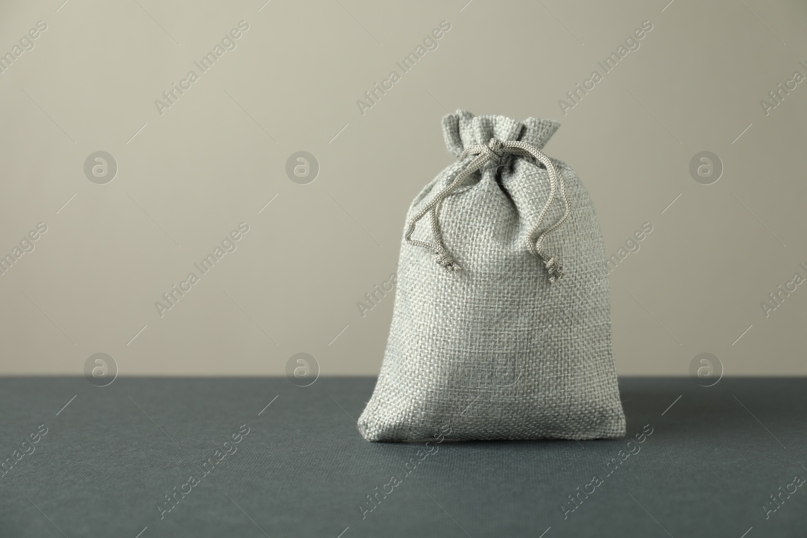 Photo of Burlap sack on gray surface against light background, space for text