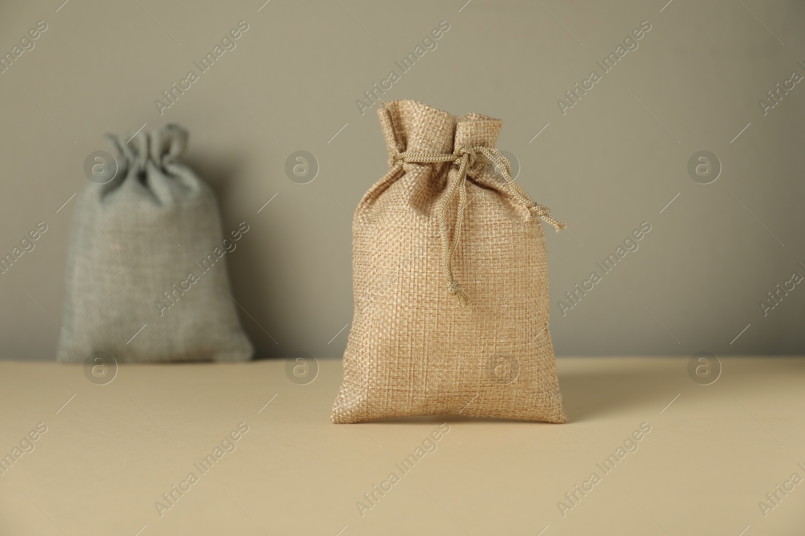 Photo of Burlap sacks on beige surface against gray background