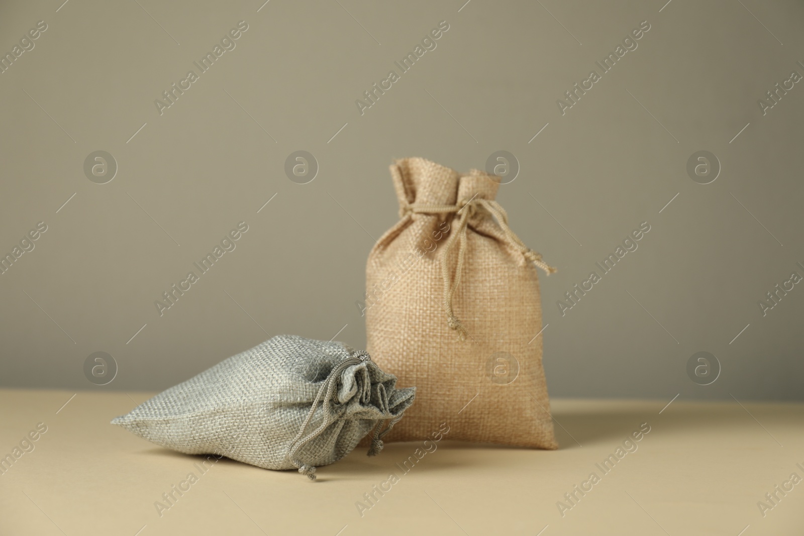 Photo of Burlap sacks on beige surface against gray background